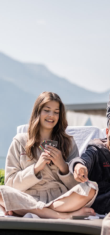 Familie spielt Karten auf der Liegewiese im Familienhotel STOCK resort in Österreich